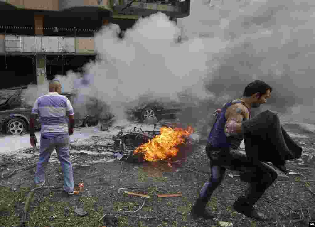 Seorang pria berjalan di depan sebuah mobil yang terbakar, di lokasi terjadinya dua ledakan di dekat Kedutaan Besar Iran di Beirut, Lebanon.