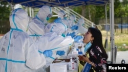 A medical worker in a protective suit conducts a nucleic acid test for a resident, following a new outbreak of the coronavirus disease (COVID-19) in Beijing, China, June 20, 2020.