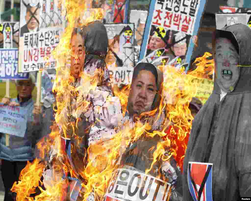 Demonstran anti-Korea Utara membakar patung pemimpin Korut, Kim Jong-il (kanan), Kim Jong-un dan pendiri Korut Kim Il-sung selama protes di pusat kota Seoul.