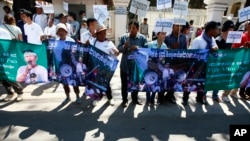 Protesters hold banner printed with detained activist Vorn Pao in front of the Appeals Court during a rally in Phnom Penh, Cambodia, Monday, March 24, 2014. The protesters demanded the release of the 21 anti-government demonstrators, including Vorn Pao, who were arrested during a crackdown on a labor protesting in January. (AP Photo/Heng Sinith)