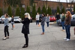 Staff of "Food and Friends," a food distribution service for people with life-challenging illnesses, practice social distancing as they listen to District of Columbia Mayor Muriel Bowser speak in Washington, March 16, 2020.