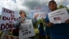 FILE - Protesters holds signs as they stand with others outside an event where Republican presidential candidate, Donald Trump and New Jersey Gov. Chris Christie were to appear on May 19, 2016 in Lawrenceville, N.J. 