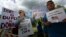 FILE - Protesters holds signs as they stand with others outside an event where Republican presidential candidate, Donald Trump and New Jersey Gov. Chris Christie were to appear on May 19, 2016 in Lawrenceville, N.J. 