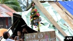 临时栖身处里的菲律宾儿童。简易圣诞树上挂的牌子上写着：美国帮忙 圣诞快乐