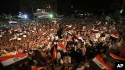 Pendukung presiden terguling Mesir, Mohamed Morsi meneriakkan slogan sambil memegang foto Morsi dan melambai-lambaikan bendera Mesir seusai sholat taraweh di kota Nasr, Kairo (10/7).