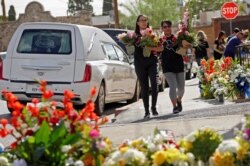 FILE - People carry flowers during a tribute to the victims of a mass shooting at a Walmart store in El Paso, Texas, Aug. 18, 2019.