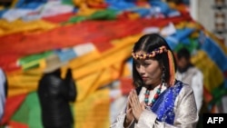 中国西藏自治区首府拉萨的大昭寺外面，一名穿着藏族传统服装的中国游客正在合什拍照（2016年9月10日）。