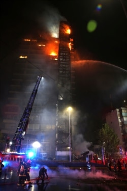 Firefighters work to put out the flames rising from the Enel Energy Europe building set on fire by protesters against the rising cost of subway and bus fares, in Santiago, Chile, Oct. 18, 2019.