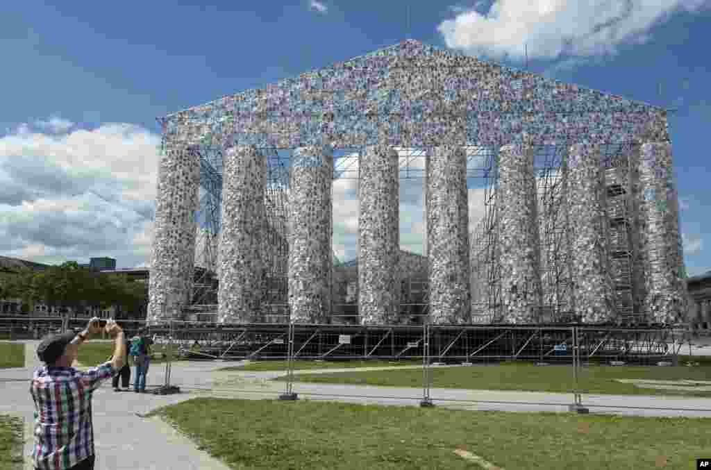Seorang pria mengambil foto karya seni &lsquo;The Parthenon of Books&rsquo; oleh artis Argentina Marta Minujin, yang masih dalam tahap konstruksi, sebagai persiapan dalam pameran senin mendatang di Kassel, Jerman.