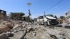 FILE - Somali policemen look at the wreckage of a destroyed car at the scene of a suicide attack at a checkpoint outside the main base of an African Union peacekeeping force in the Somali capital, Mogadishu, Jan. 2, 2017.