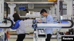 中国广东一家工厂的工人正在对一工业机器人进行调试。2019年3月1日. 