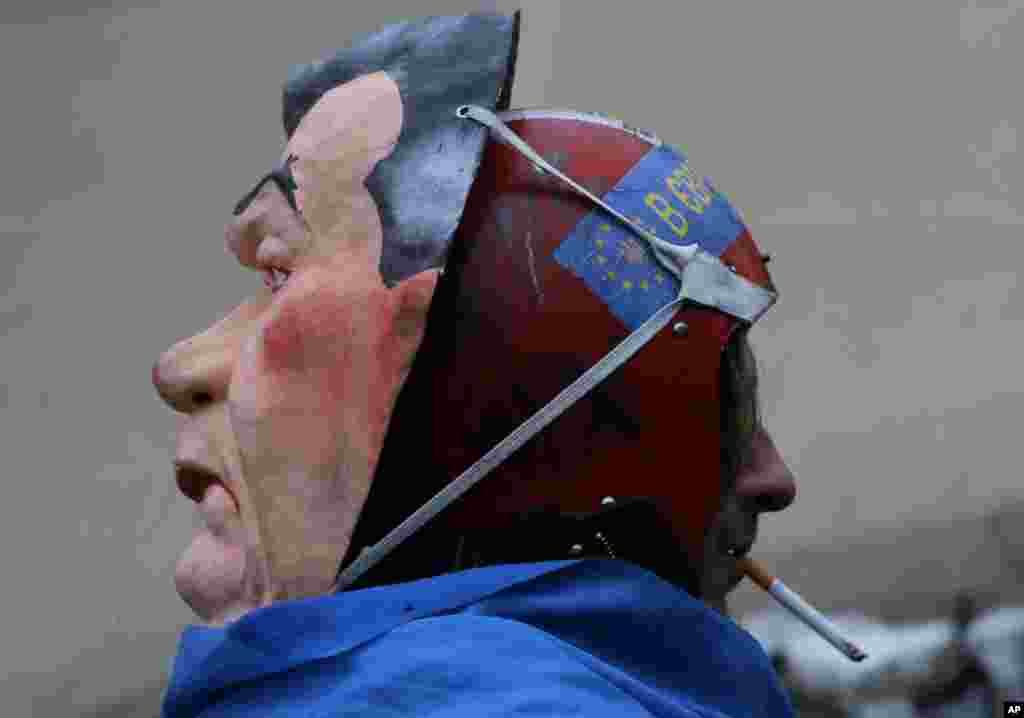 Aktivis anti pemerintah mengenakan helm dan topeng Presiden Ukraina Viktor Yanukovich, merokok di Lapangan Kemerdekaan, ibukota Kiev, Ukraina. 