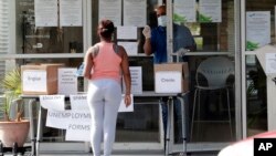 2020年4月8日戴着口罩的工作人员和索取失业表格的妇女交谈