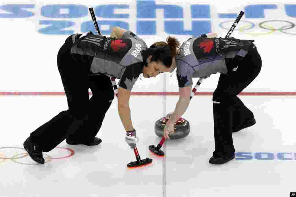Jill Officer dari Kanada (kiri) dan Dawn McEwen (kanan) menyapu es pada pertandingan cabang curling melawan Denmark pada Olimpiade Musim Dingin, Sochi, Rusia, 13 Februari 2014.