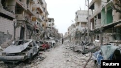Les véhicules et les bâtiments endommagés sont vus dans la ville de Douma dans la Ghouta orientale, le 25 février 2018.
