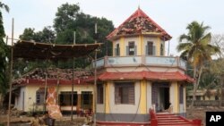 Indian policemen guard the damaged structures at the spot where a massive fire broke out during a fireworks display at the Puttingal temple complex in Paravoor village, Kollam district, southern Kerala state, India, Monday, April 11, 2016.