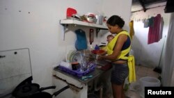 지난 3월 브라질 레시페에서 한 여성이 소두증으로 태어난 아기를 안고 집안일을 하고 있다. (자료사진)