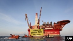 This handout photo taken by Greenpeace on August 25, 2012 shows Greenpeace activists holding a banner in front of the Gazprom 'Prirazlomnaya' oil drilling platform during their protest in the Barents Sea as the Gazprom support boat secures the area.