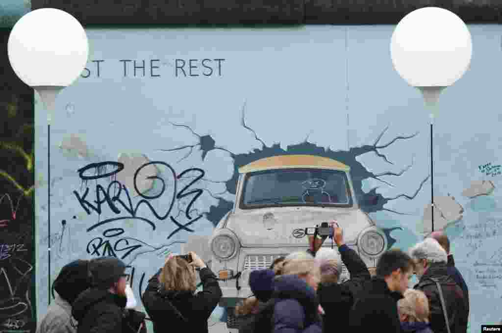 مردم در &laquo;گالری شرقی&raquo; از آثار هنری با مضمون سالگرد فروریختن دیوار برلین عکس می&zwnj;گیرند - ۱۸ آبان ۱۳۹۳ 