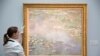 Une assistante de gallerie pose le tableau Nympheas de Claude Monet lors d'une photo-call pour la vente d'art à la maison de ventes Sotheby's à Londres le 18 juin 2014. REUTERS / Neil Hall
