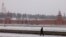 FILE - A pedestrian walks along an embankment of the Moskva river with the Kremlin on the background during a snowfall in Moscow, Jan. 21, 2022. 