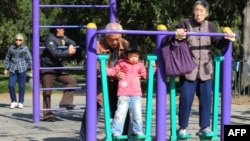 中国第七次人口普查数据显示，中国人口“低速增长”，趋于老化。图为北京天坛公园里的老年人和他们的独生子女的孙辈在锻炼身体。（法新社2011年10月25日资料照）