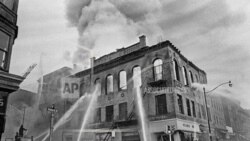 资料照片 - 消防员将水流引向新泽西州纽瓦克王子街和法院街拐角的一座着火的建筑，在那里持续了四天的致命暴力和抢劫后来被称为纽瓦克骚乱。（1967年7月15日）(美联社照片/马蒂·莱德汉德，档案)