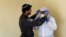 An Israeli police officer helps a Health Ministry inspector put on protective gear before they go up to the apartment of a person in self-quarantine as a precaution against the coronavirus spread, in Hadera, Israel, March 16, 2020.