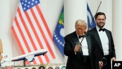 Президент Дональд Трамп держит саблю после разрезания ею торта на балу главнокомандующего. За спиной Трампа стоил вице-президент Дж. Д. Вэнс. 20 января 2025 года, Вашингтон