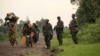 Displaced families walk past M23 rebels at Rumangabo, after government troops abandoned the town 23 km (14 miles) north of the eastern Congolese city of Goma, July 28, 2012. 