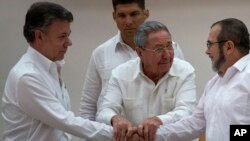 FILE - Cuba's President Raul Castro (C) encourages Colombian President Juan Manuel Santos (L) and Commander the Revolutionary Armed Forces of Colombia or FARC, Timoleon Jimenez, to shake hands, in Havana, Cuba, Sept. 23, 2015. 