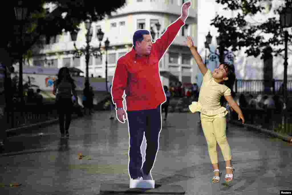 Seorang anak perempuan Venezuela melompat ke arah gambar mendiang Presiden Hugo Chavez di Plaza Bolivar di kota Caracas, Venezuela.