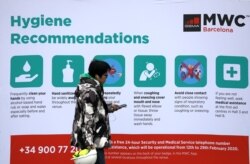 一名男子走过西班牙巴塞罗那世界移动大会的保持个人卫生的相关信息。（2020年2月12日）