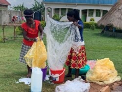 Women wash polythene bags at Reform Africa, in Mpigi district, Uganda. (H. Athumani/VOA)