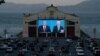 People watch from their vehicles as President Donald Trump, on left of video screen, and Democratic presidential candidate former Vice President Joe Biden speak during a presidential debate watch party at Fort Mason Center in San Francisco, Oct.