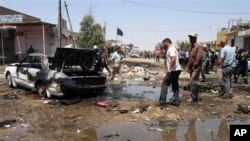 Warga berkumpul di sekitar sebuah mobil yang rusak akibat serangan bom mobil di Karbala, 20 kilometer dari kota Baghdad, Irak (29/4). Lima bom dilaporkan meledak di sekitar wilayah yang mayoritas penduduknya warga Syiah ini, Minggu (28/4).