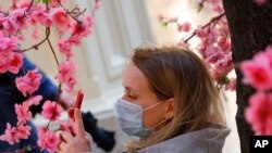 زنی با ماسک در مقابل گل های مصنوعی فروشگاهی در مسکو - ۱۰ ژوئن ۲۰۲۱