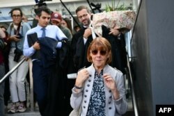 Gisele Pelicot leaves the Avignon, France, courthouse flanked by her lawyers carrying a bouquet of flowers gifted to her as they exited the courtroom during the trial of her former husband Dominique Pelicot.