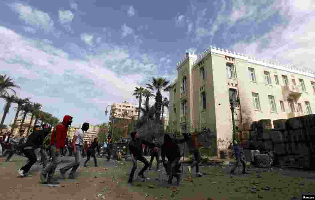 当反对埃及总统摩尔西的抗议者2013年1月25日在开罗解放广场同镇暴警察发生冲突时，向镇暴警察扔石头。