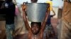A child carrying a bucket full of water walks in mud after a storm in the airport camp in Bangui, Central African Republic, Sunday Feb. 2, 2014. Over 130,000 have seemed refuge outside the airport, living in dismal conditions, as fighting between Muslim 