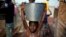 A child carrying a bucket full of water walks in mud after a storm in the airport camp in Bangui, Central African Republic, Sunday Feb. 2, 2014. Over 130,000 have seemed refuge outside the airport, living in dismal conditions, as fighting between Muslim 