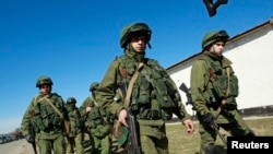 在克里米亚首府辛菲罗波尔城外，据信是俄罗斯军人的士兵列队走在乌克兰军队某驻地外。（2014年3月3日）