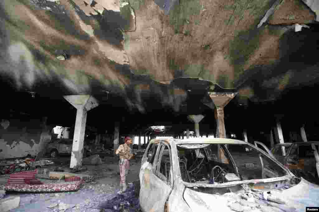 A security guard looks at a damaged car during a visit by human rights activists to a community hall in Sana&#39;a, Yemen, that was struck by an airstrike during a funeral on Oct. 8.