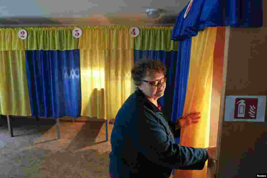 Election commission worker Vera Pozhidaeva demonstrates the readiness of a polling station for Sunday's referendum in the eastern Ukrainian city of Lugansk, May 10, 2014.