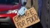 FILE - Holding a sign, a jobless man panhandles at an intersection in Falls Church, Virginia, April 3, 2020. 