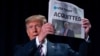 President Donald Trump holds up a newspaper with the headline that reads "ACQUITTED" at the 68th annual National Prayer Breakfast, at the Washington Hilton, Feb. 6, 2020, in Washington.