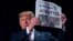 President Donald Trump holds up a newspaper with the headline that reads "ACQUITTED" at the 68th annual National Prayer Breakfast, at the Washington Hilton, Feb. 6, 2020, in Washington.