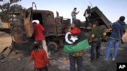 人们在查看被联军炸过的忠于卡扎菲部队的武器