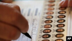 Seorang warga mengisi surat suaranya di sebuah TPS di Wellsville, Kansas (6/11). Data pendahuluan jajak pendapat nasional menunjukkan 73 persen warga AS keturunan Asia memilih Obama sebagai Presiden.