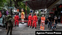 People walk past statues featuring characters from the Netflix series Squid Game at a food court to attract visitors in Surabaya on Oct. 21, 2021.